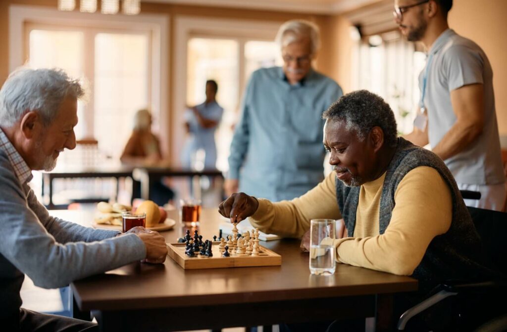 Two happy seniors enjoy playing chess in assisted living.