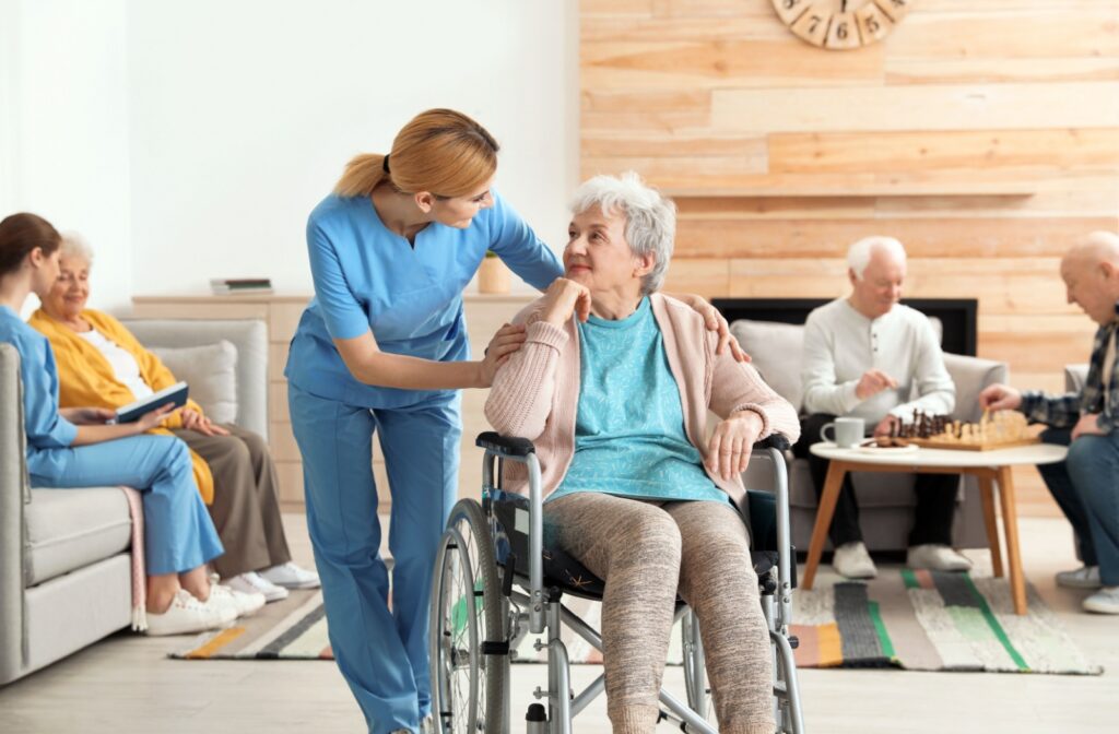 A memory care resident connecting with a staff member in the communal space, surrounded by engaged fellow residents.
